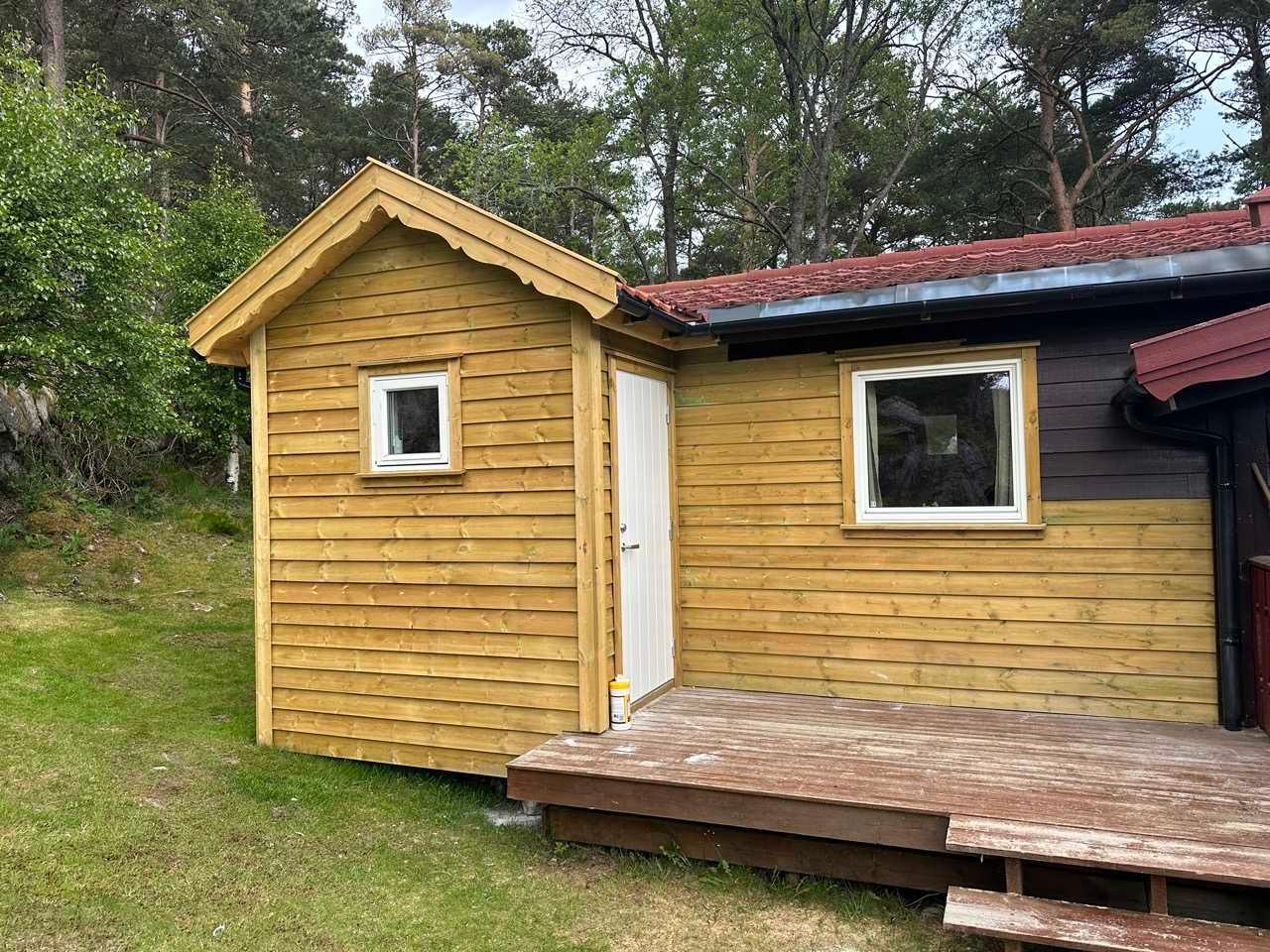 Nytt lite bygg i gul trekledning med terrasse